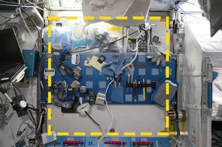 Marcada com adesivos amarelos, uma das áreas da ISS que serviram como "poços de teste" na "escavação" realizada na estação espacial: pensada para ser uma bancada de manutenção, ela é mais usada como local para guardar ferramentas e outros objetos NASA/International Space Station Archaeological Project, CC BY