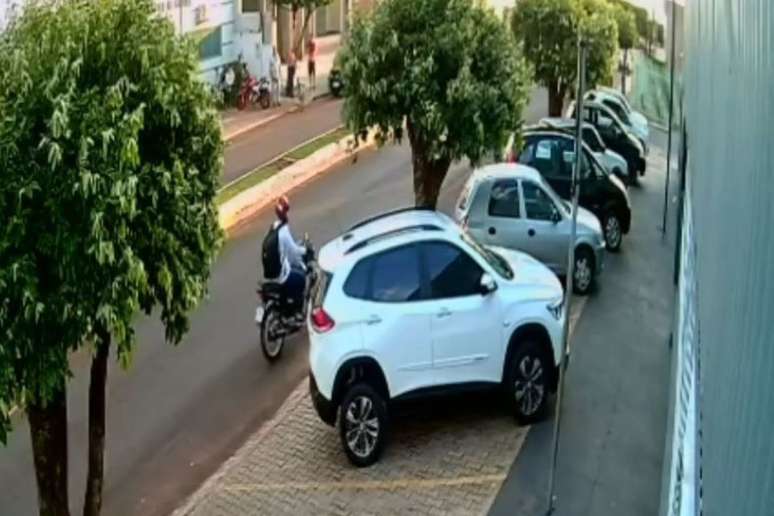 Um homem usando capacete vermelho, camisa branca e calça jeans se aproximou pelas costas do professor e atirou