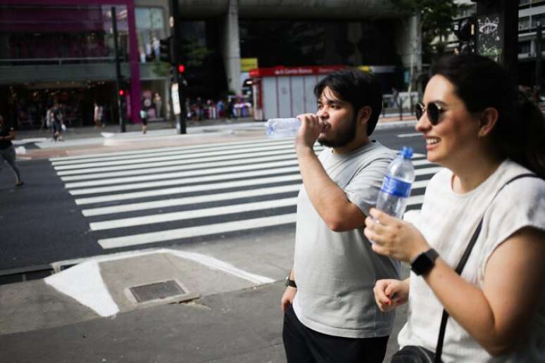 Diante do forte calor, a hidratação é essencial. Na foto, pessoas caminhando na Avenida Paulista em dia bastante quente.