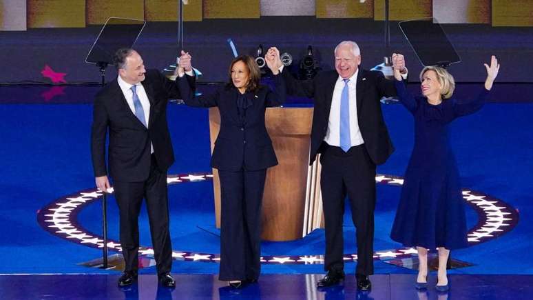 Kamala Harris e seu marido Doug Emhoff de mãos dadas com Tim Walz e sua esposa Gwen Walz, durante a Convenção Nacional Democrata