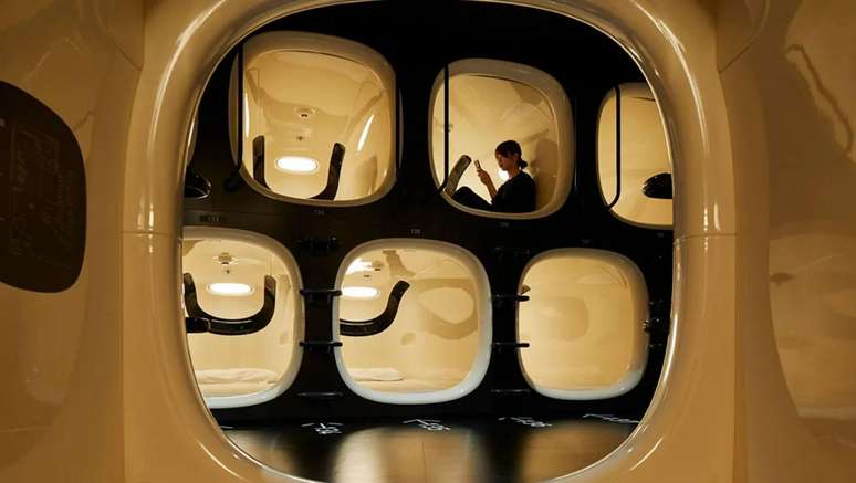 Mulher em c&aacute;psula, mexendo no celular