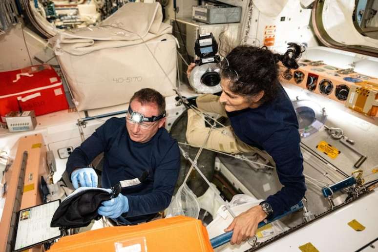 Butch Wilmore e Suni Williams trabalhando na Estação Espacial.