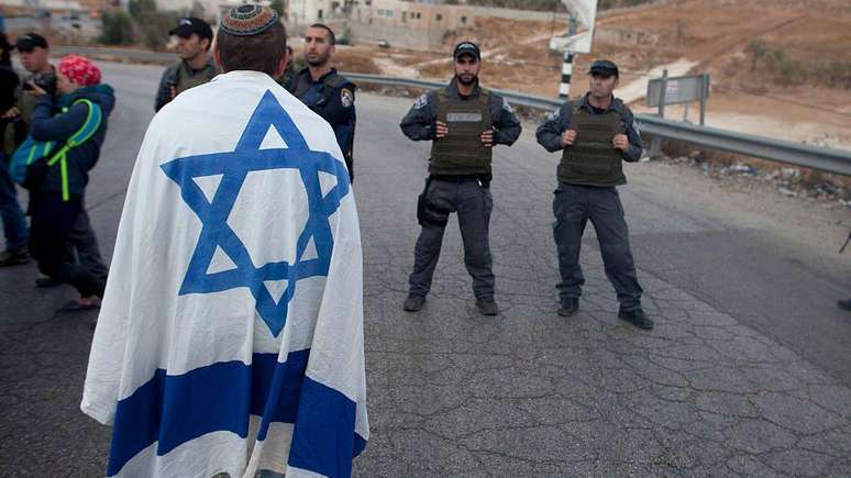 Um colono israelense diante de policiais israelenses em uma manifestação na entrada do vilarejo de Beit Sahur, na Cisjordânia