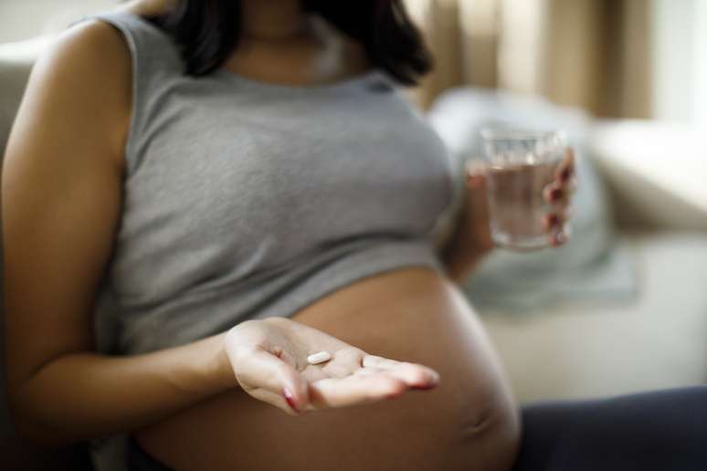 Mulher gravida com comprimido na mão