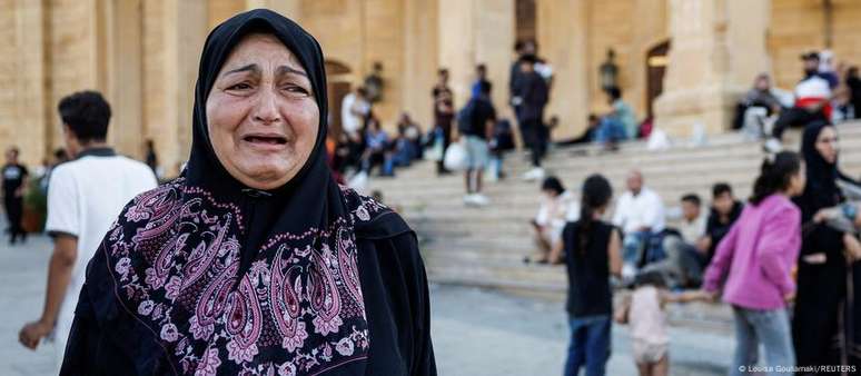 Mulher libanesa que precisou deixar sua casa devido aos bombardeios chora a morte de Hassan Nasrallah, em Beirute