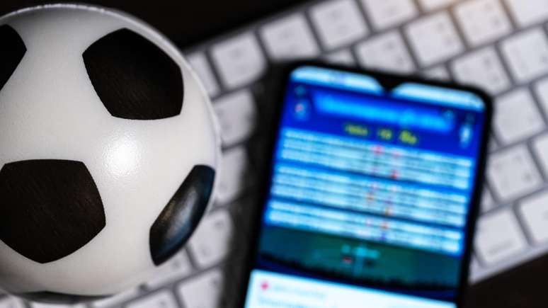 Bola de futebol, teclado de computador e celular