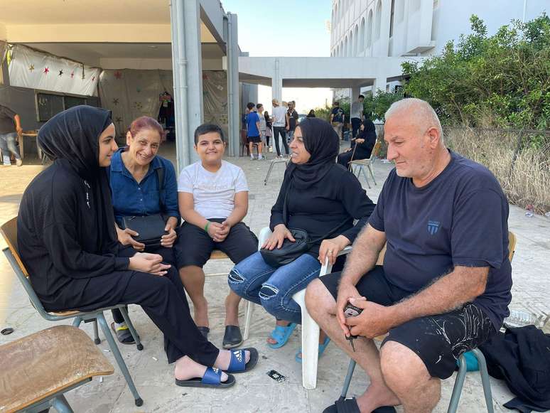 Kamal Mouhsen e sua família sentam-se no pátio da escola que agora é sua casa.