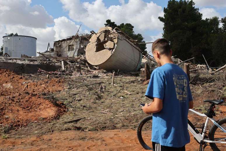 Menino de bicicleta observa os escombros de um edifício destruído em Hod HaSharon, no centro de Israel, após um ataque de mísseis iranianos no dia 2 de outubro de 2024