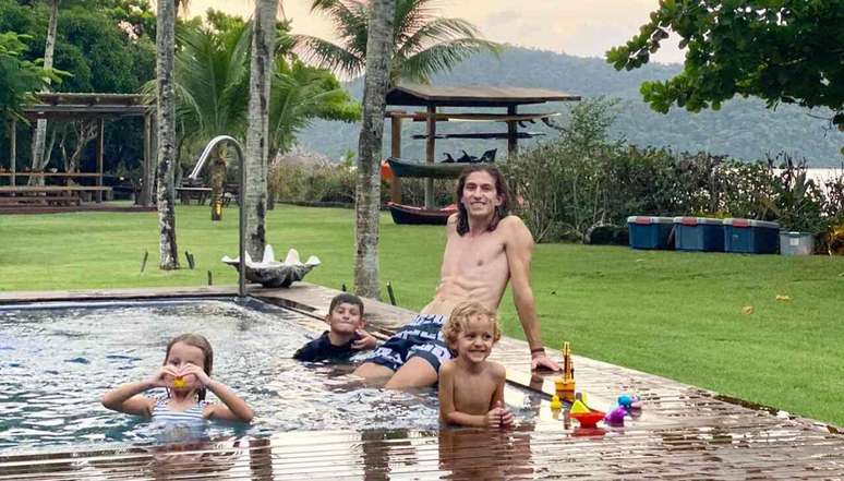 Entrenador disfrutando de la piscina con sus tres hijos –