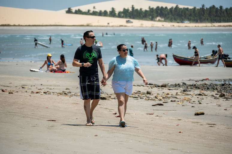 O casal passeou pela praia onde turistas e praticantes de esportes aquáticos se divertem