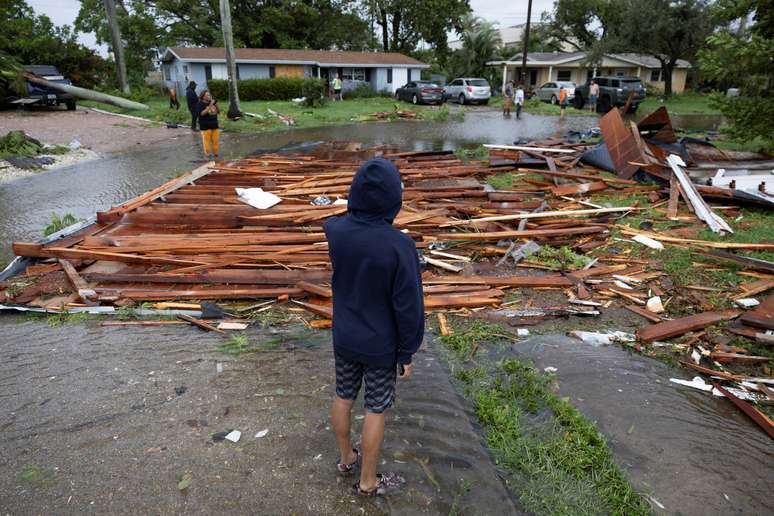 Um homem olha para um telhado na rua de uma casa próxima depois que um tornado atingiu a área enquanto o furacão Milton se aproximava de Fort Myers, Flórida, EUA, em 9 de outubro de 2024.