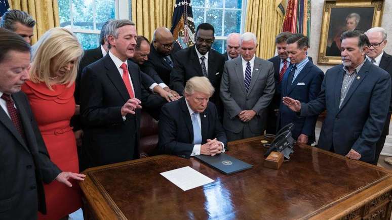 Trump rezando ao lado de líderes religiosos no Salão Oval da Casa Branca durante sua presidência