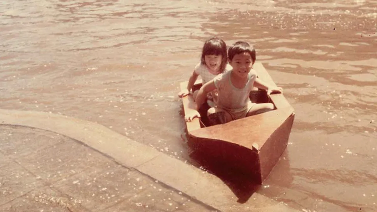 Kotchakorn Voraakhom e seu irmão brincam em um barco feito pelo pai, durante a enchente de 1983 em Bangkok