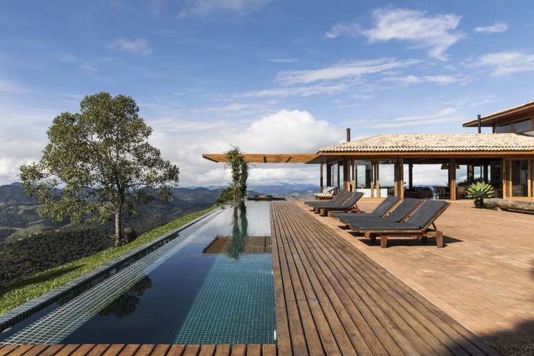 Este deck de madeira cumaru, ao redor da piscina com borda infinita, garante estabilidade e integra o espaço à natureza ao redor Projeto: Sabella Arquitetura |