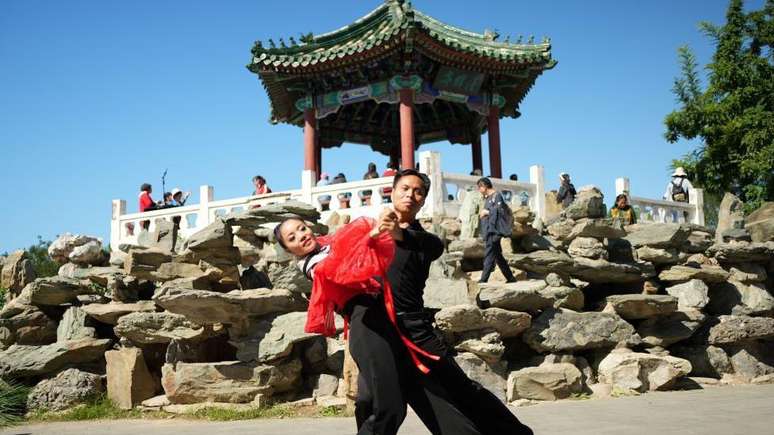 Dançarinos no Ritan Park, em frente a um templo tradicional chinês