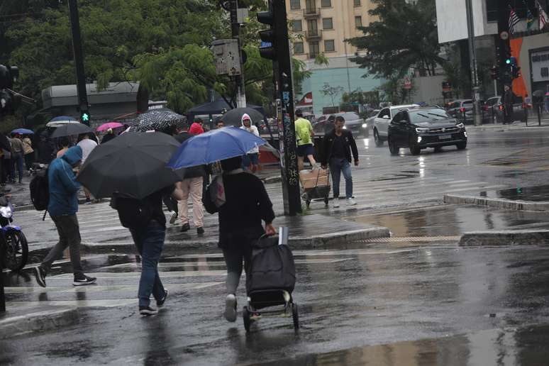 Com a chegada de uma frente fria em São Paulo, pedestres correm e se protegem da chuva repentina e do frio que faz nesta tarde de eleições municipais na Avenida Paulista, região centro-sul da capital paulista, neste domingo (27)