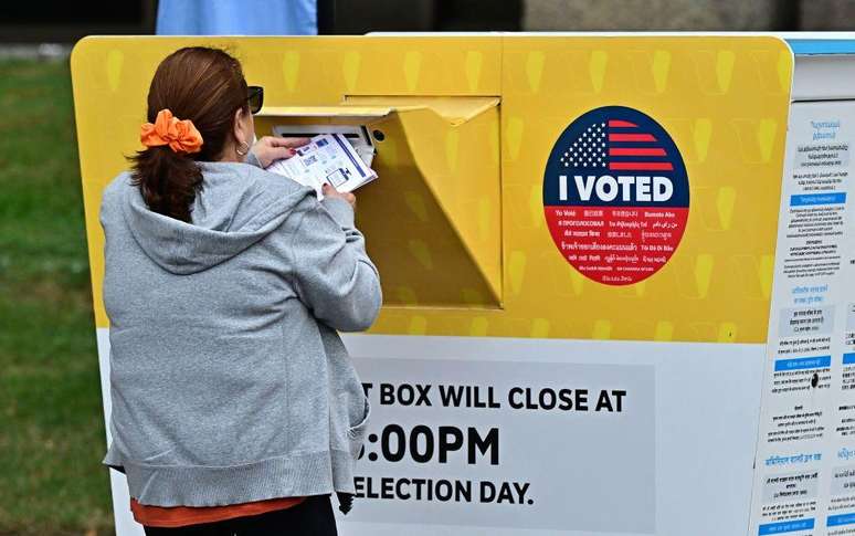 Eleitora entrega uma cédula de votação em Los Angeles, Califórnia milhões de eleitores já votaram na votação antecipada