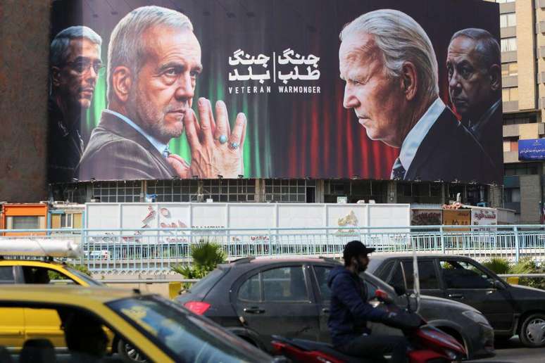 Um outdoor em Teerã mostra o presidente iraniano e um líder da Guarda Revolucionária frente a frente com Biden e Netanyahu