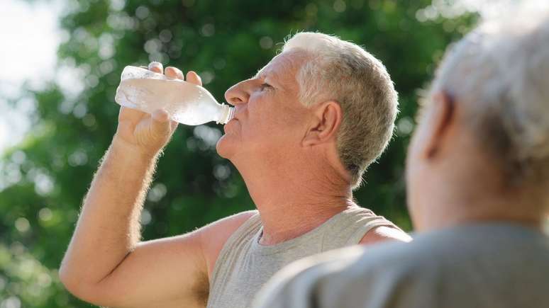 Idoso bebendo água com calor