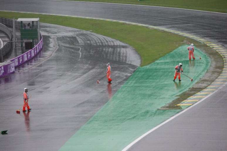 Funcionários tentam escoar a água da chuva presente na curva do S do Senna após tempestade atingir o autódromo de Interlagos na tarde deste sábado, adiando os treinos classificatórios.