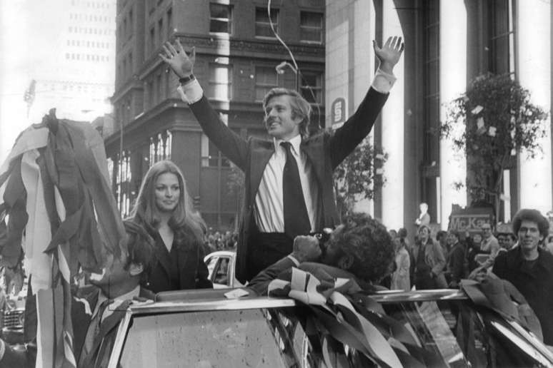 Karen Carlson sit in car and Robert Redford stands with hands raised in a scene from the film 'The Candidate', 1972. (Photo by Warner Brothers/Getty Images)