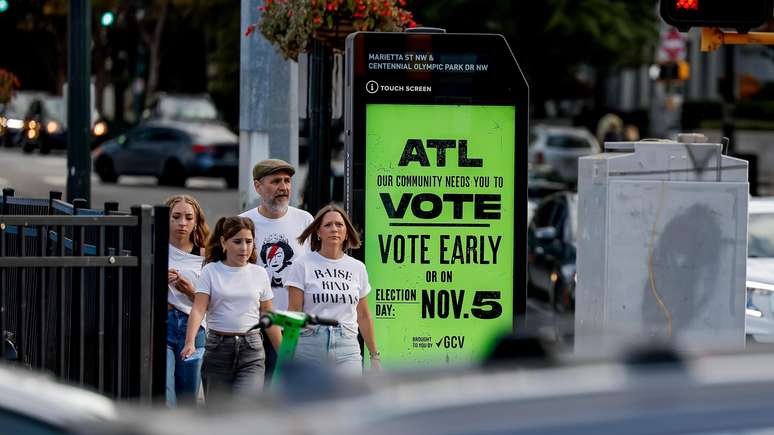 Pessoas passam por um outdoor incentivando a votação, no centro de Atlanta, Geórgia