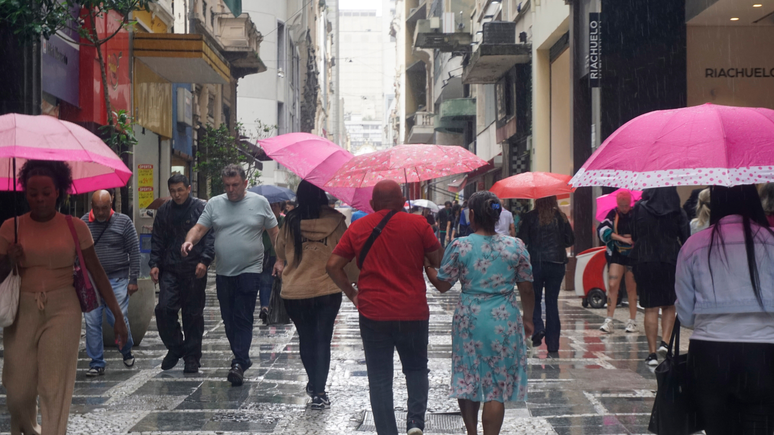 Pedestres se protegem da chuva na região central de São Paulo, na tarde desta quarta- feira (6).