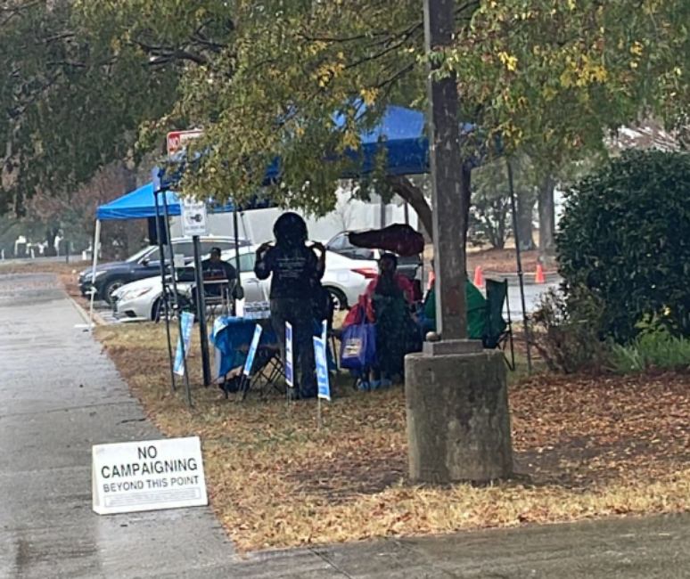 Voluntários democratas em frente a uma escola que recebe votação 