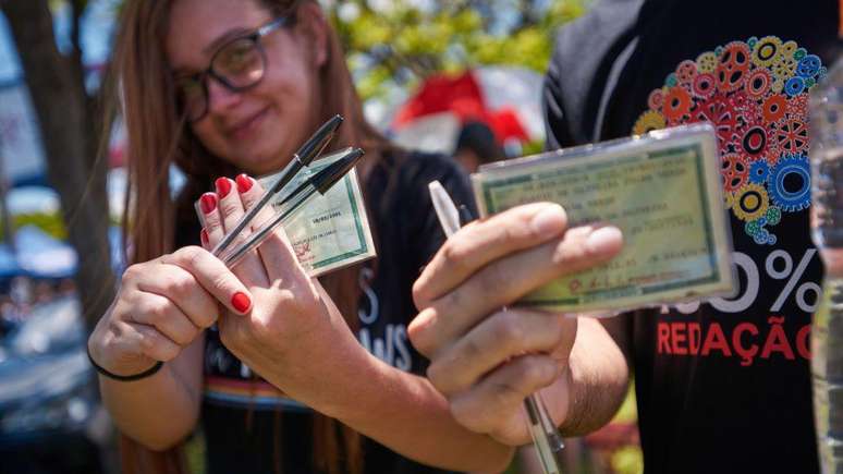 Duas estudantes chegam para fazer o Enem em Franca, interior de São Paulo, segurando RG e canetas 