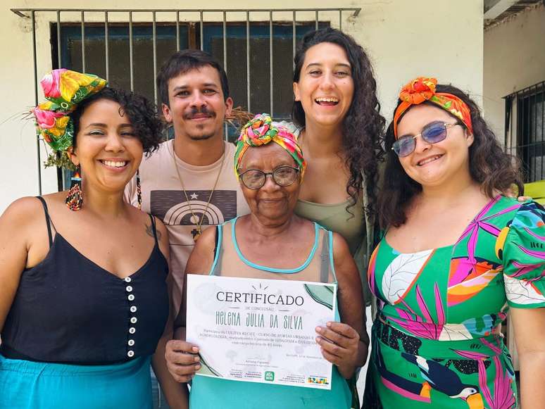 Helena Júlia, 79 anos, segura diploma do curso de agroecologia, rodeada de técnicos e professores.