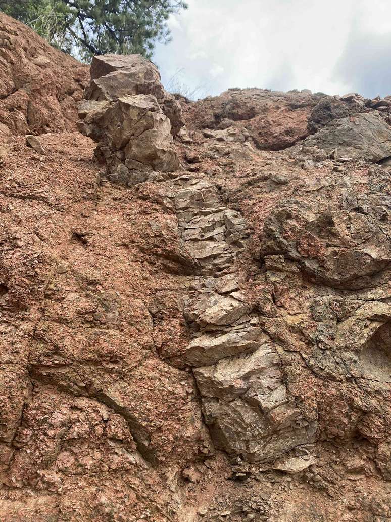 Um lado do penhasco mostrando uma longa faixa de Tava de cor mais clara cortando o granito de Pikes Peak. A injeção aqui tem 5 metros de altura