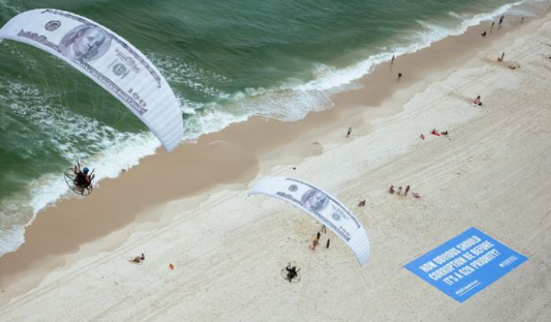 Parapentes com notas gigantes de dólar sobrevoaram a Barra, no Rio, em protesto da Transparência Internacional cobrando ação do G20 contra corrupção