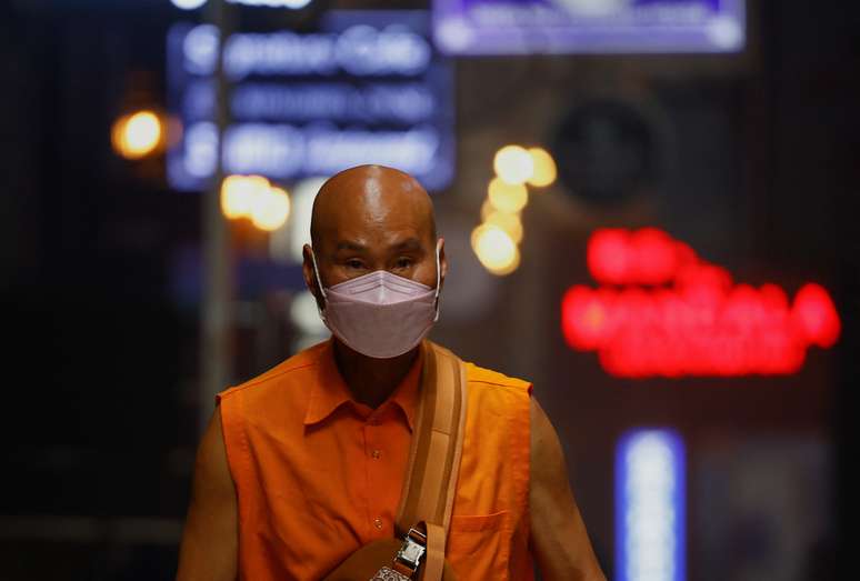 Monge usa m&aacute;scara protetora enquanto caminha em mercado na &Iacute;ndia