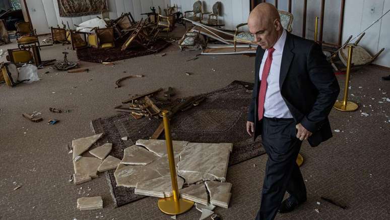 O ministro Alexandre de Moraes caminha em sala do STF destruída