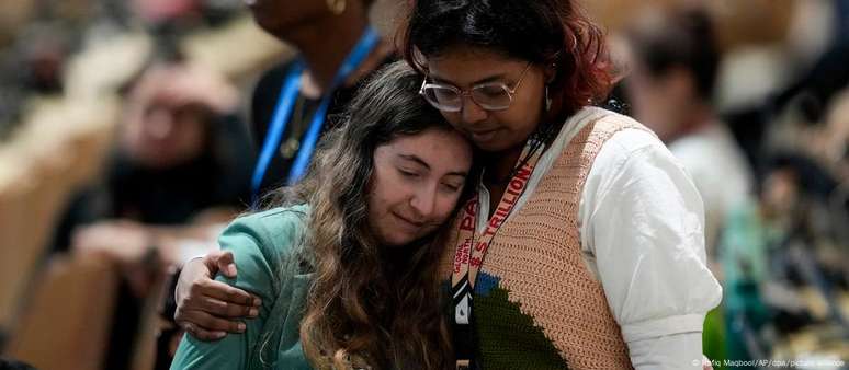 Participantes se abraçam durante a sessão plenária de encerramento da COP29, em Baku, Azerbaijão