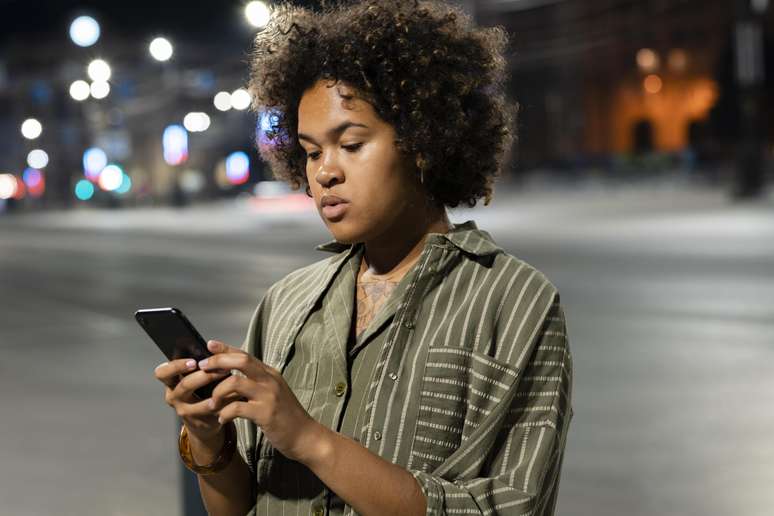 Mulher preocupada olhando notícias no celular.