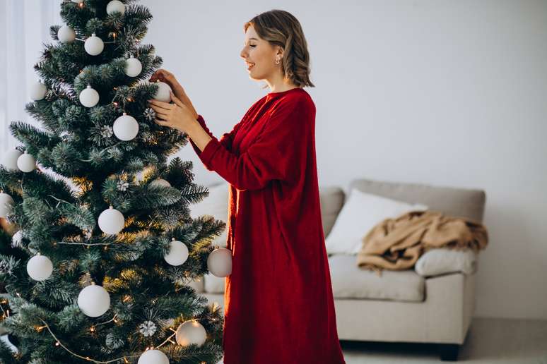 Mulher decorando árvore de Natal.