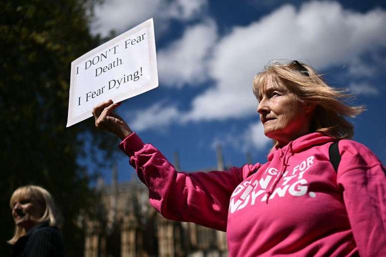 Uma ativista com deficiência da Dignity in Dying segura um cartaz durante protesto em apoio às propostas para legalizar a morte assistida no Reino Unido