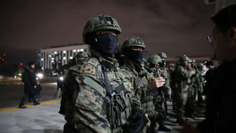 Soldados sul-coreanos tentam entrar na assembleia nacional em Seul, Coreia do Sul. Yoon Suk Yeol anunciou que estava dando o passo, que promulga o governo temporário dos militares, durante um discurso televisionado na terça-feira, dizendo que era fundamental para a defesa da ordem constitucional do país. Desde que assumiu o cargo, há dois anos, Yoon tem lutado para impor as suas agendas contra um parlamento controlado pela oposição