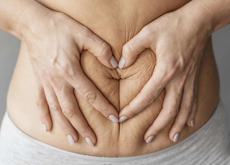 Mulher com as mãos em volta da barriga.