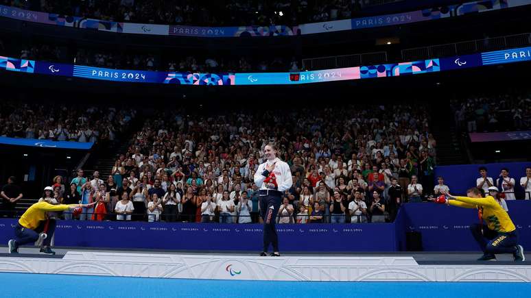 Debora e Beatriz Borges Carneiro saúdam a vencedora da medalha de ouro nos 100 metros nado peito, a britânica Louise Fiddes