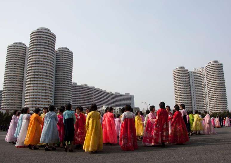 Mulheres vestidas com trajes tradicionais em frente a blocos de apartamentos