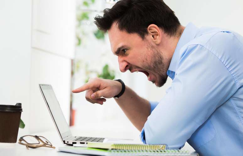 Homem irritado gritando com o computador.