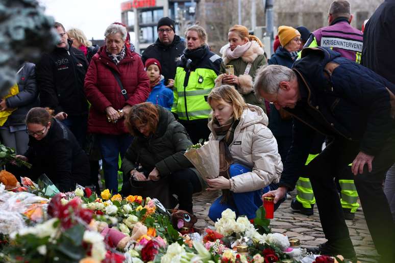 Pessoas deixam velas e homenagens florais às vítimas perto do local onde um carro atropelou uma multidão em um mercado de Natal de Magdeburg, em Magdeburg, Alemanha, em 21 de dezembro de 2024.