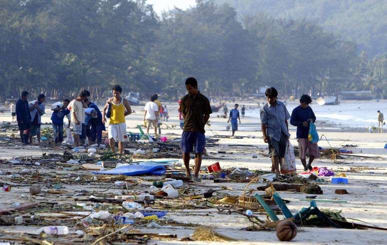 Na Tailândia, imagem de 27 de dezembro de 2004 mostra moradores caminhando entre escombros ao longo da costa da praia de Pathong