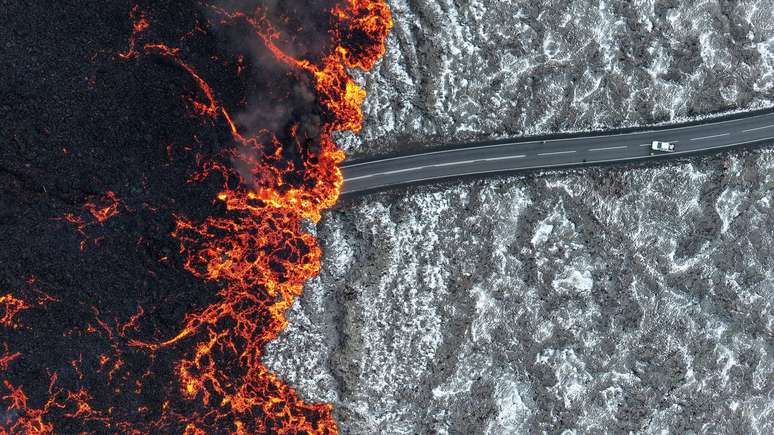 Lava flui por uma estrada após erupção vulcânica na Península de Reykjanes, na Islândia