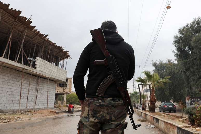 Em 29 de dezembro, um combatente do governo s&iacute;rio montando guarda com seu rifle em um posto de controle em Muadamiyat al-Sham, nos arredores de Damasco