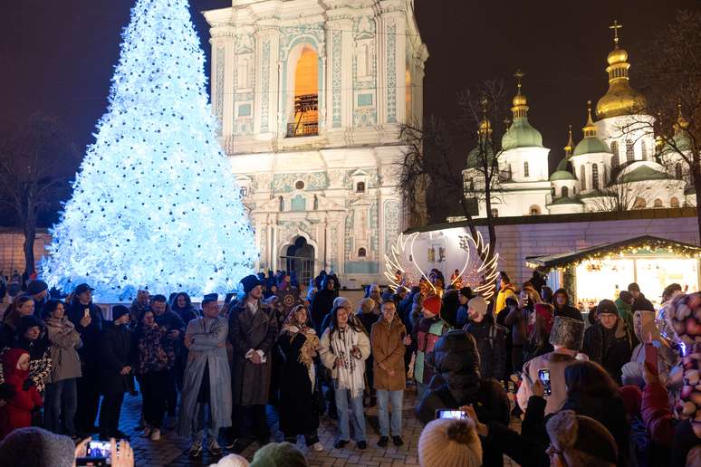 Pessoas se reúnem ao lado de uma árvore de Natal para celebrar a véspera de Ano Novo, em meio ao ataque da Rússia à Ucrânia, em frente à Catedral de Santa Sofia em Kiev