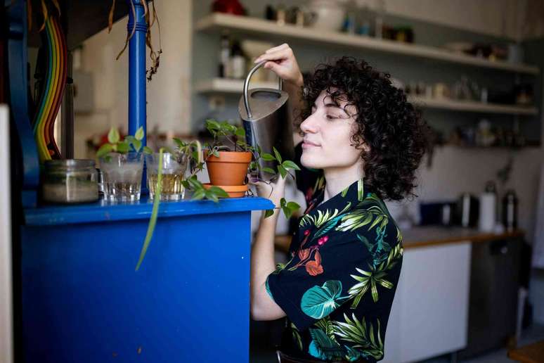 pessoa regando pequenos vasos de plantas