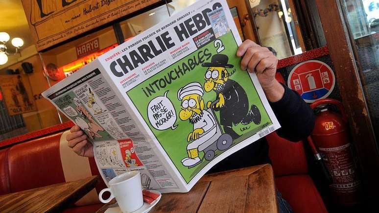 As charges da Charlie Hebdo zombam de todas as religiões - esta capa mostra uma paródia do filme 'Os Intocáveis', onde um religioso islâmico em uma cadeira de rodas é empurrado por um judeu